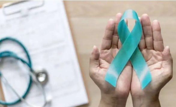 Hands cupping a teal awareness ribbon, with a stethoscope and paperwork blurred in the background.