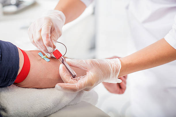 Close up of doctor hands taking blood from male vein into tube by catheter | Dr Sandeep Nayak close-up of surgeons' gloved hands using a scalpel during an operation on a patient.