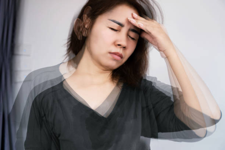 Woman rests her hand on her forehead with eyes closed, conveying headache or stress.