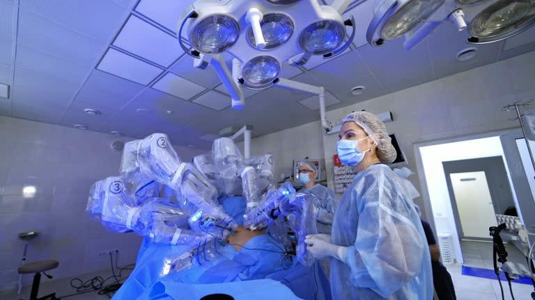 robotic thyroid surgery Surgeons in PPE operate a robotic-assisted system with multiple robotic arms during surgery in a sterile operating room.