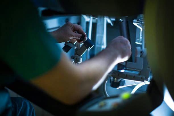 robotic thyroid surgery Close-up of a technician's hands adjusting knobs on a mechanical device in a workshop setting.